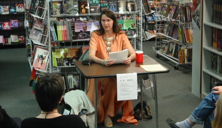 S.N.Arly sitting at a table at Dreamhaven Books and Comics