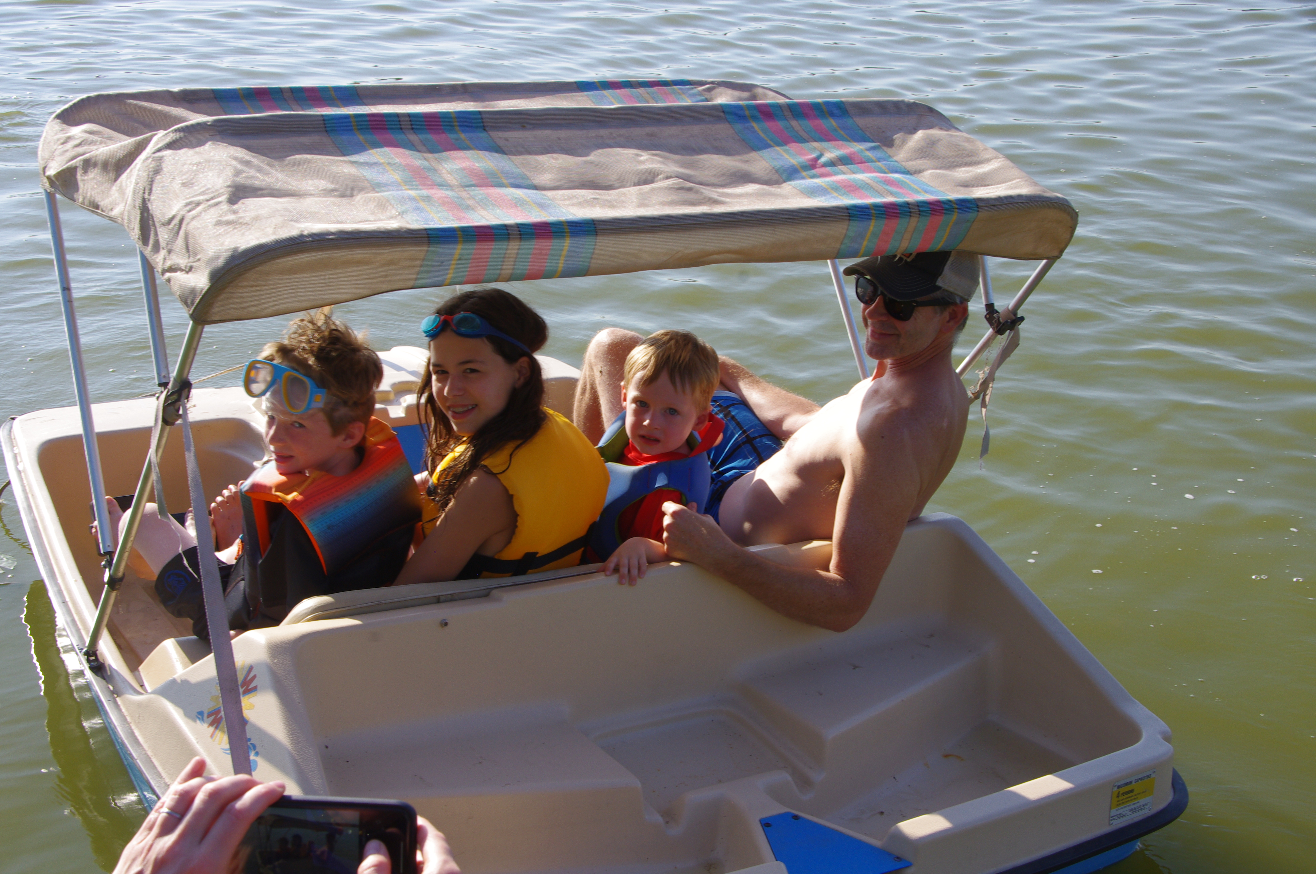 Three kids and an adult in a peddle boat.